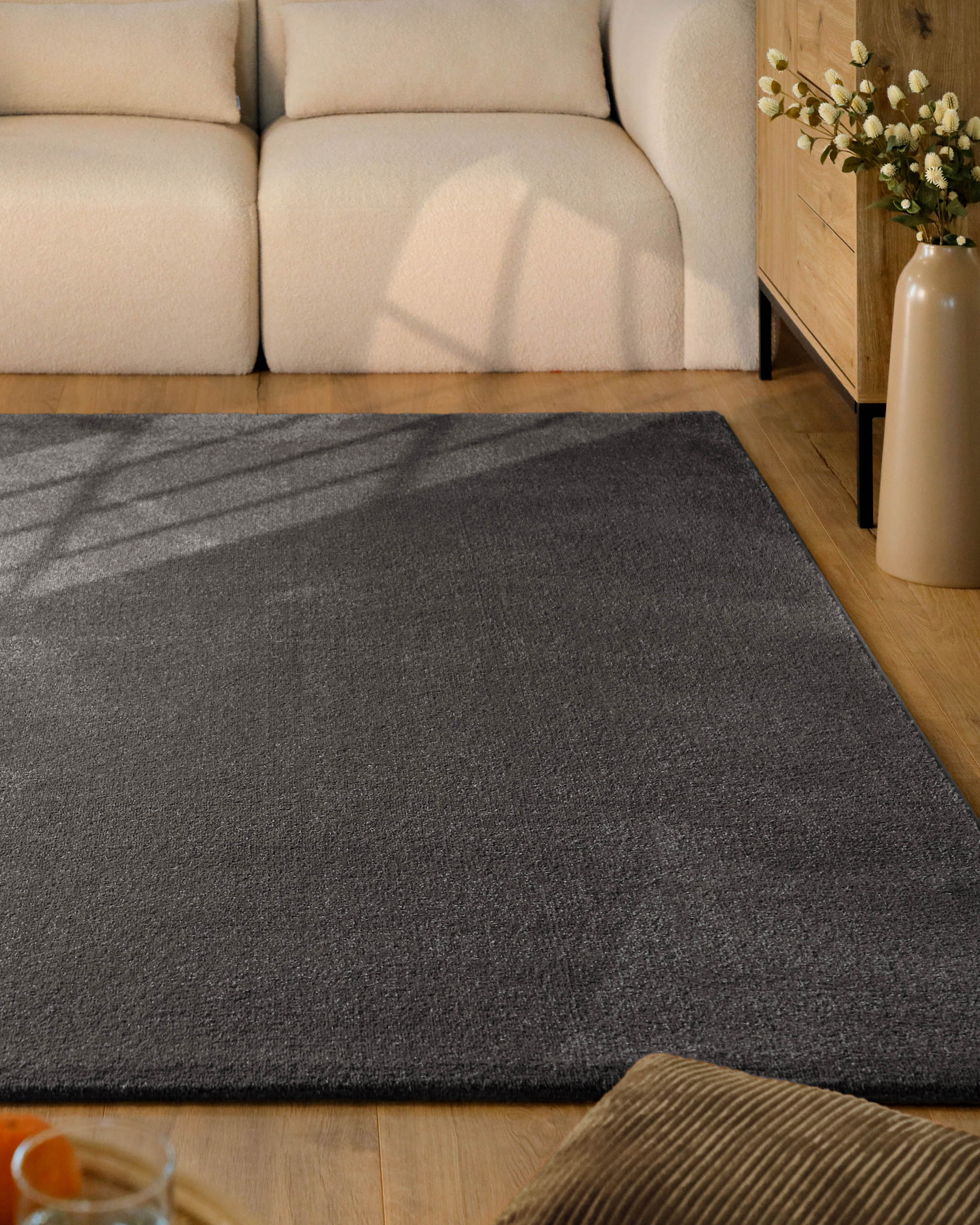 Kurzflor Teppich Vegas Anthrazit im Wohnzimmer vor Sofa auf Holzboden, moderner Kontrast