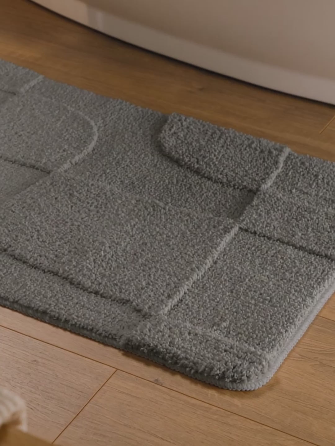 Badteppich von BathKing by WECONhome Davie Basalt Grau Video Nahaufnahme von Flor und Kante, Hand bewegt den Teppich und zeigt Materialstruktur